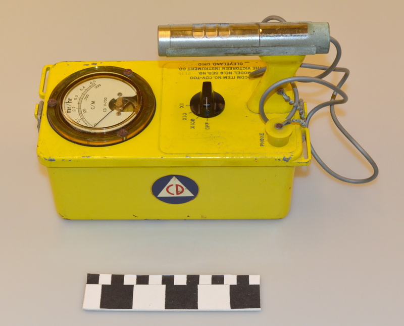 Image of a yellow geiger counter device with Civil Defense logo on the side.