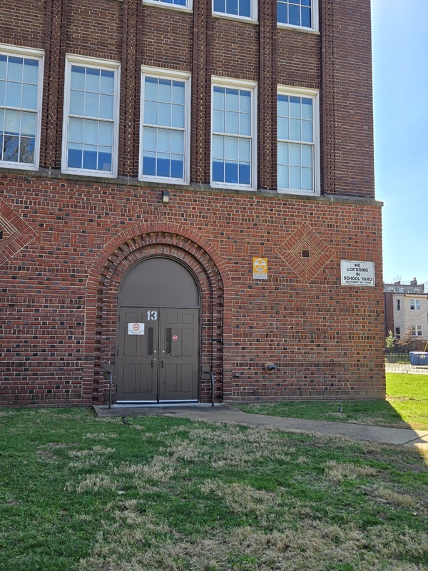 View of a fallout shelter sign near an entryway to the Sigel School building.