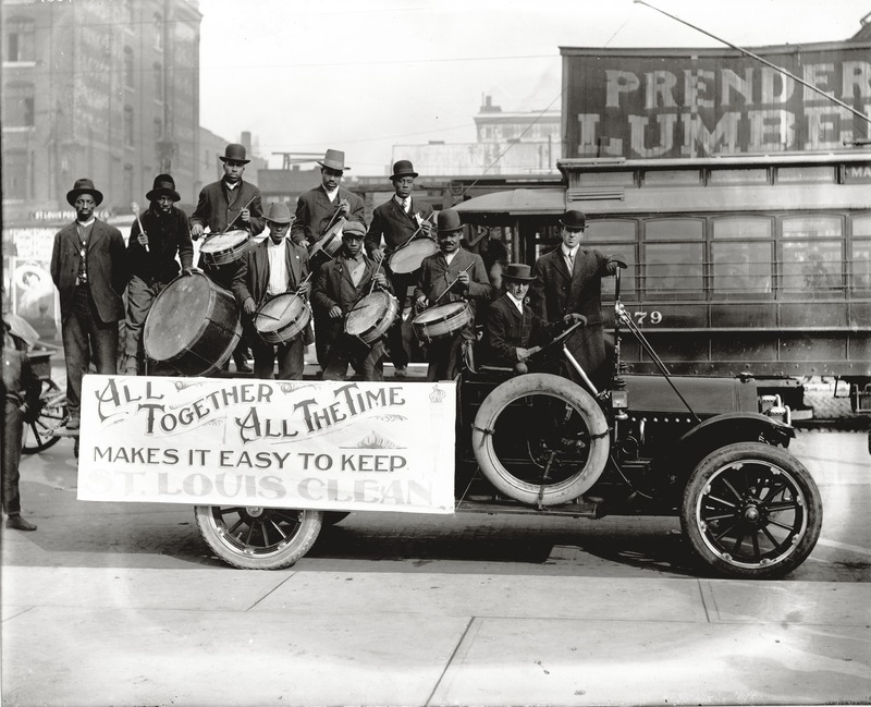 An African American Drumming Group Perform on The Back of a Truck Carrying a Banner That Reads "all Together All the Time Makes It Easy to Keep St. Louis Clean" On Market Street