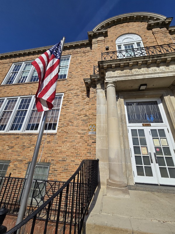 Close up view of fallout shelter sign on Woerner School building, with American Flag in the foreground.