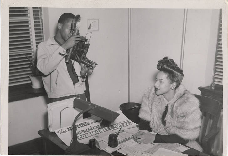 African American Woman at Desk Being Photographed