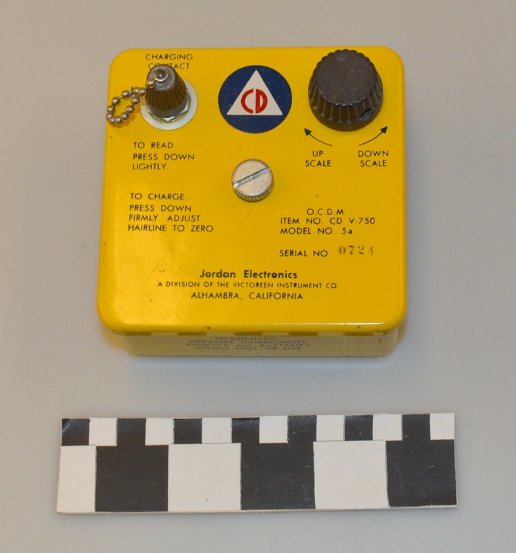 Image of a yellow dosimeter charging device with Civil Defense logo on the top.