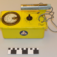 Image of a yellow geiger counter device with Civil Defense logo on the side.