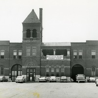 Historic photo of brick building with Office of Civil Defense sign and cars parked nearby.