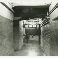 Historic image of a child standing in a basement hallway at a school.