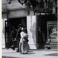 WOMAN PASSING A GROUP OF MEN ON THE SIDEWALK IN FRONT OF THE STRAND AND COLUMBIA THEATERS AT 419 AND 425 NORTH 6TH STREET.