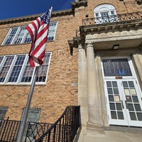Close up view of fallout shelter sign on Woerner School building, with American Flag in the foreground.