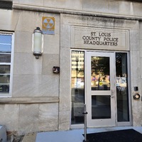 Close up view of doorway to County Police building with fallout shelter sign next to it.