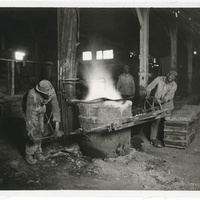 AFRICAN AMERICAN WORKERS MOVING A CRUCIBLE OF MOLTEN METAL AT THE SCULLIN STEEL FOUNDRY.