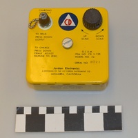 Image of a yellow dosimeter charging device with Civil Defense logo on the top.